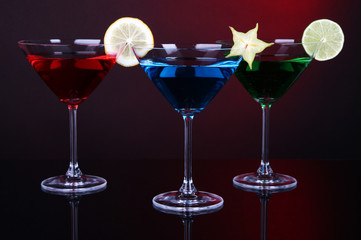 Alcoholic cocktails in martini glasses on dark red background
