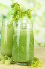 Glasses of green celery juice on bamboo mat, on green