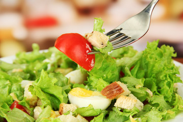 Caesar salad on white plate, close up on bright background