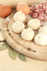 Raw dumplings and ingredients on wooden table