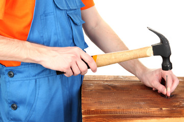 Builder hammering nails into board isolated on white