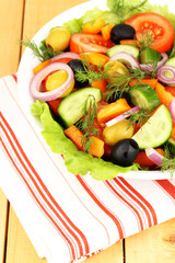 Fresh salad in plate on wooden table