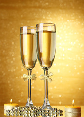 Two glasses of champagne on bright background with lights
