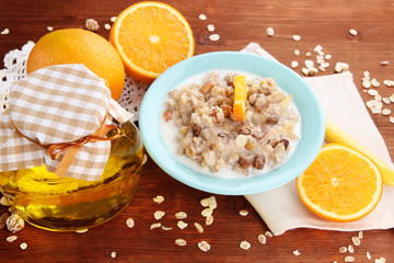 Useful oatmeal in bowl with fruit on wooden table close-up