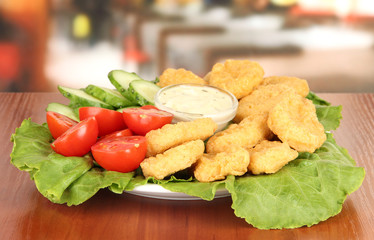 Fried chicken nuggets with vegetables and sauce on table in
