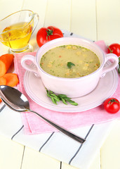 Nourishing soup in pink pan on wooden table close-up