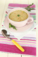 Nourishing soup in pink pan on wooden table close-up