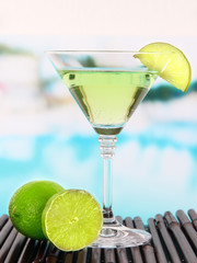 Green cocktail with lime on table on bright background