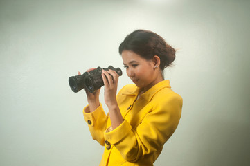 Pretty young Asian businesswoman  holding a binoculars.