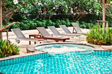 Beach chairs near swimming pool in tropical resort , Thailand.