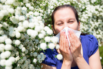 Allergic woman sneezing in handkerchief