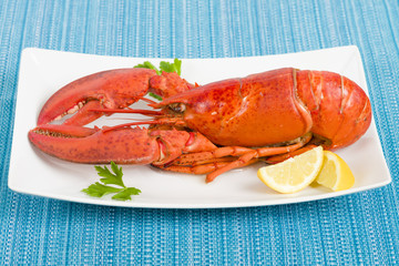 Lobster and lemon wedges on a blue background. © paul_brighton