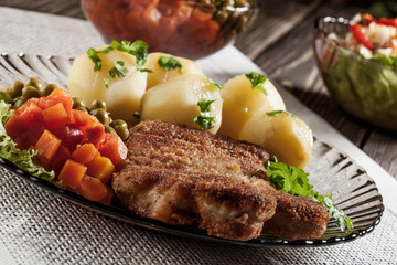 Breaded chop and potatoes. Dark light.