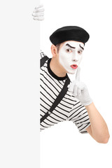 Fototapeta na wymiar Male mime artist holding a blank panel and gesturing silence wit