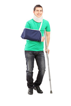 Full length portrait of a smiling male with broken arm and crutc
