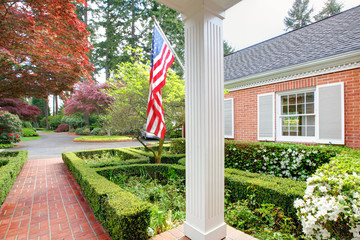 American old brick home with flag and classic garden.