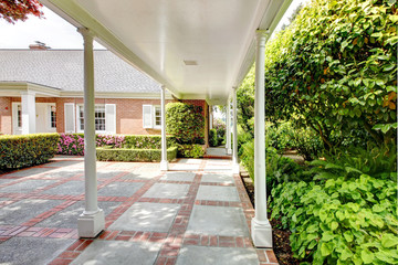 Brick red house with English garden and white window shutters.