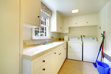 Laundry room with white old cabinets in large historical home.