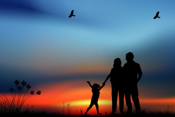 Fototapeta premium Silhouettes of happy parents having good time with their little