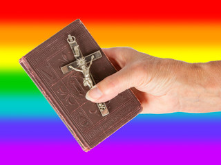 Old hand (woman) holding a very old bible, rainbow flag © michaklootwijk