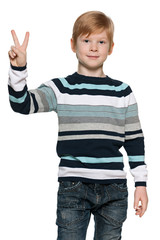 Red-haired young boy holds victory sign