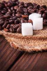 Fototapeta na wymiar coffee beans with sugar cubes on wooden background