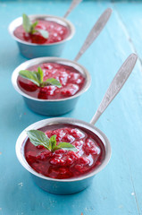 Raspberry sauсe with mint leaf on blue wooden background