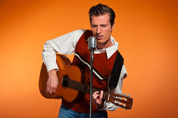 Naklejka premium Retro fifties rock and roll singer playing acoustic guitar.