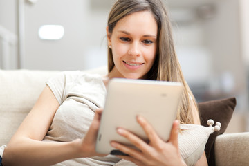 Young woman using a tablet on sofa at home