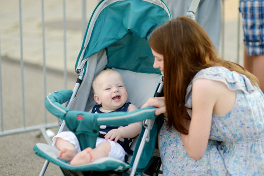 Young mother talking to her baby in a stroller