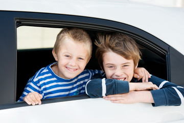 zwei lachende jungs schauen aus autofenster