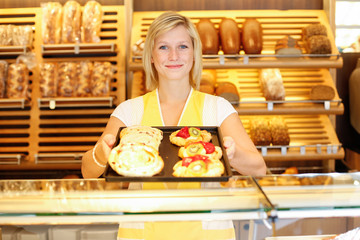 Shopkeeper in baker shop with tablet full of cake