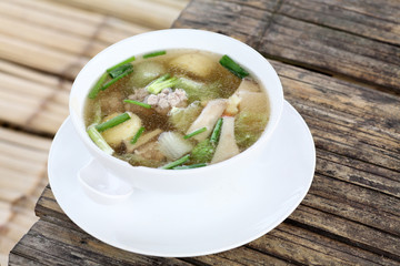 Mild soup with vegetables, pork and bean curd on a bamboo table