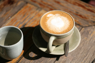 a cup of hot cappuccino on a wooden table