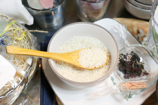 Rice grains in a white bowl with wooden spoon