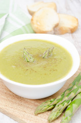 cream soup of asparagus and green peas in a bowl with toast