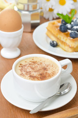 cup of cappuccino, belgian waffles with blueberries and egg