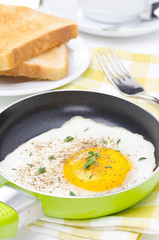 Fried eggs in a frying pan, crisp toast, coffee and orange juice