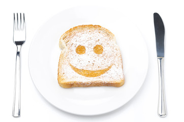 Toast with a smile of powdered sugar on a plate, fork and knife