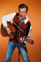 Retro fifties rock and roll singer playing acoustic guitar. Stud