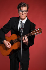 Retro fifties musician with glasses playing acoustic guitar. Stu