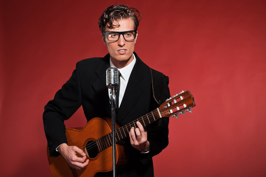 Retro fifties musician with glasses playing acoustic guitar. Stu