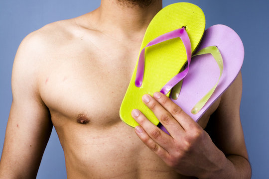 Close-up of man holding flip-flops