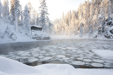 Hut near pond in winter forest
