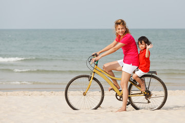 Obraz na płótnie Canvas Asian son and mother riding bicycle on beach