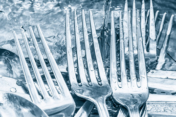 Blue toned silverware being washed with water