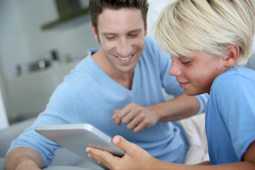 Father and son using digital tablet at home