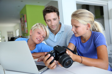 Man with teenagers looking at pictures on computer