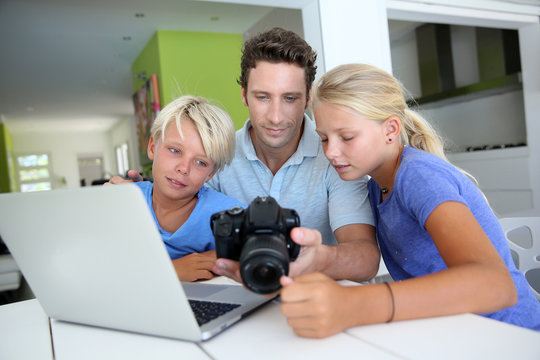 Man with teenagers looking at pictures on computer
