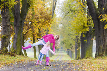 mother with her daughter in autumnal alley